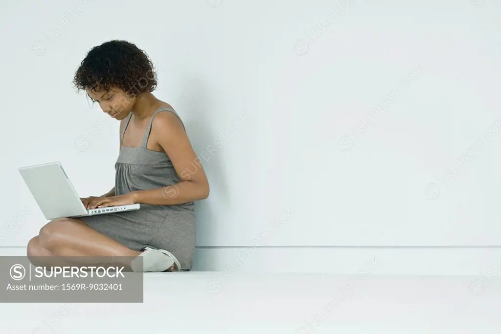 Young woman sitting on the ground, using laptop computer