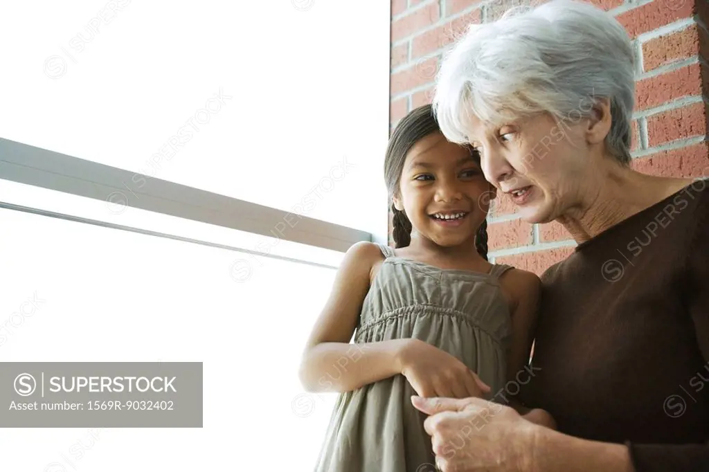 Grandmother and granddaughter cheek to cheek, holding hands, looking at each other