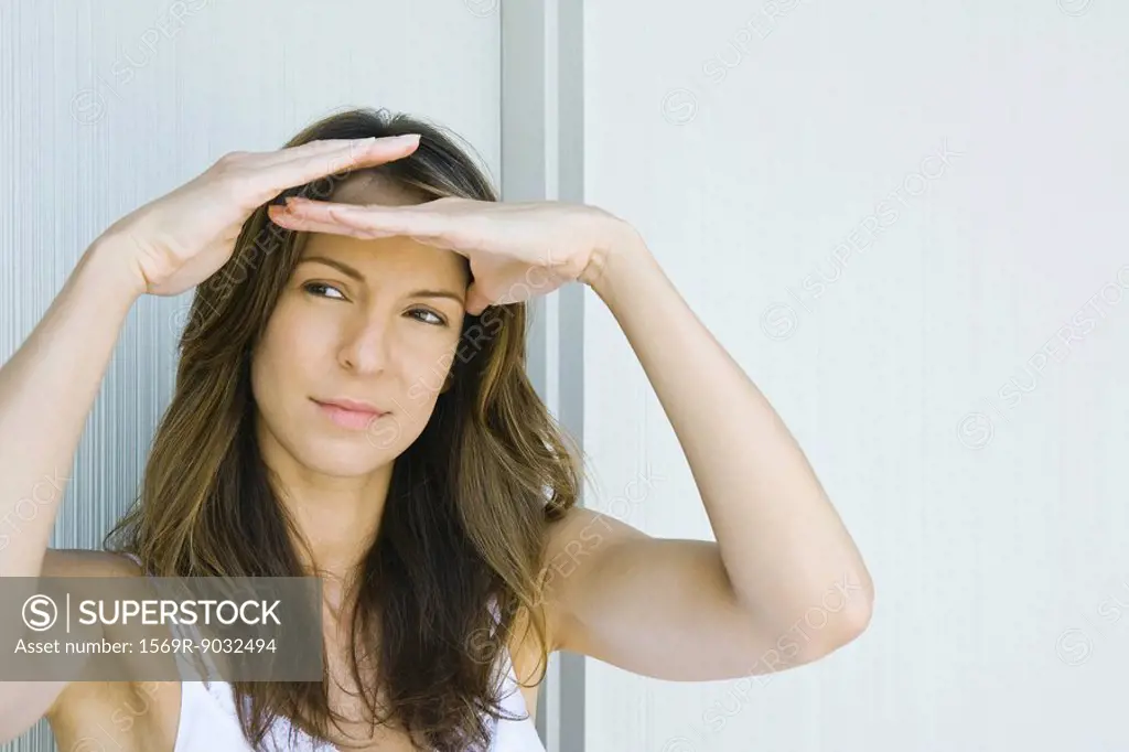 Woman shading eyes, looking away, close-up