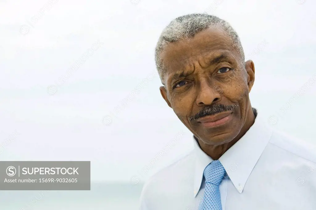Businessman, looking at camera, sea in background