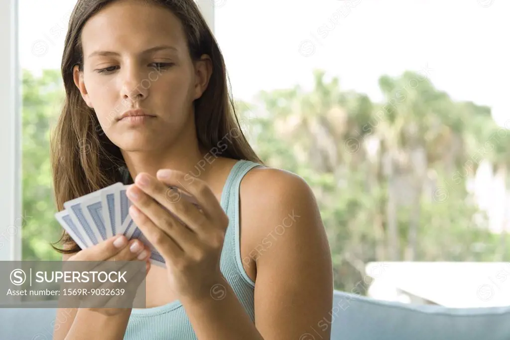 Teenage girl looking down at cards in hand, close-up