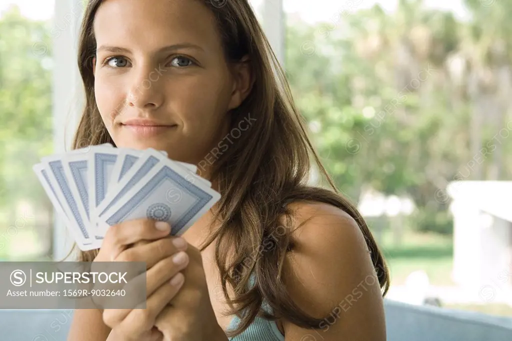 Teenage girl holding up cards, smiling at camera, close-up