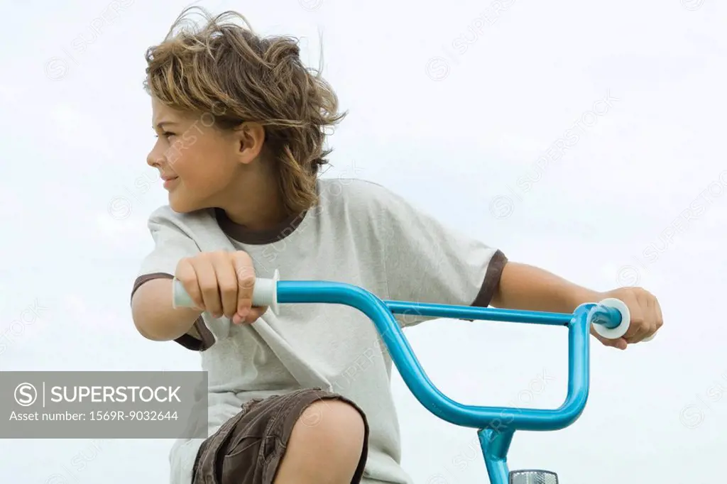 Boy riding bicycle, looking over shoulder, close-up