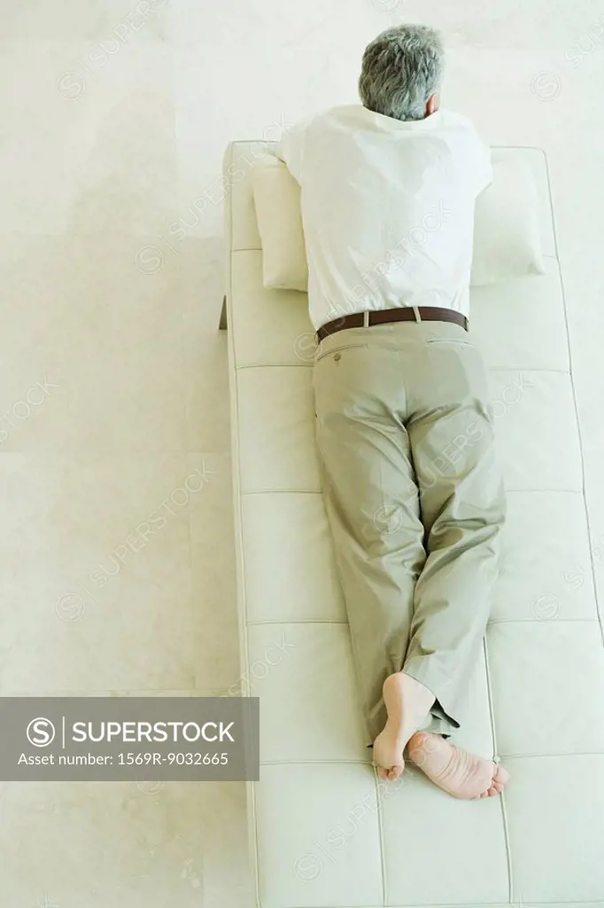 Man lying on stomach on chaise longue, high angle view, full length