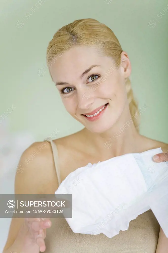 Woman holding baby diaper, smiling at camera