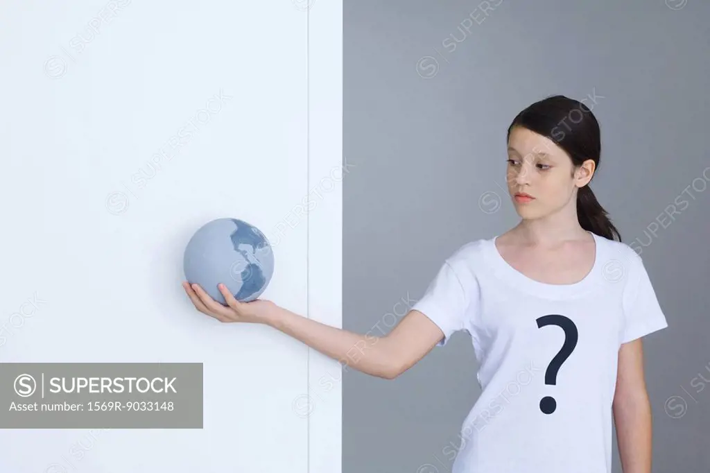Girl wearing tee-shirt printed with question mark, looking at globe