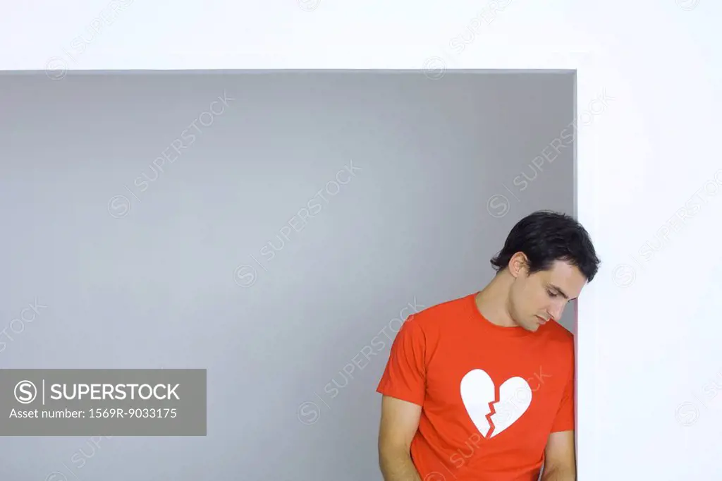 Man wearing tee-shirt with broken heart symbol, looking down
