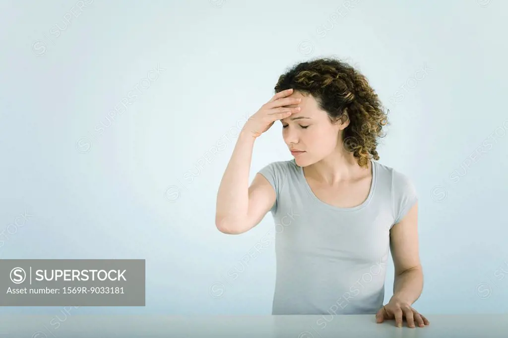 Woman holding head, eyes closed