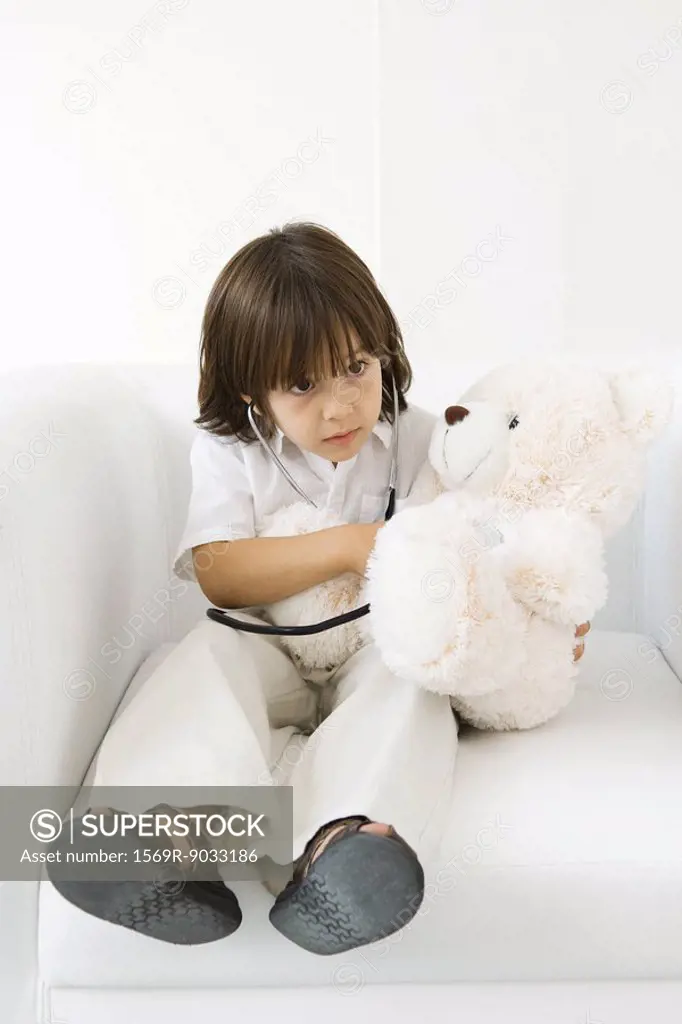 Little boy playing doctor with stuffed toy, using stethoscope