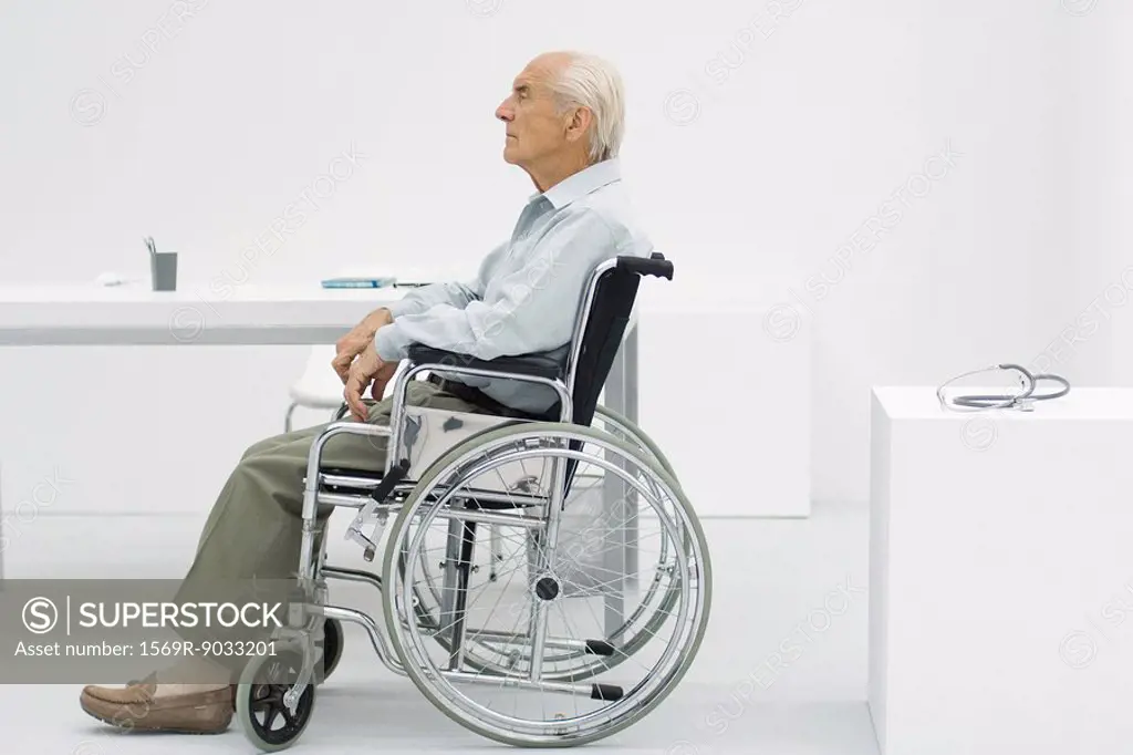 Elderly man sitting in wheelchair in doctor´s office, side view