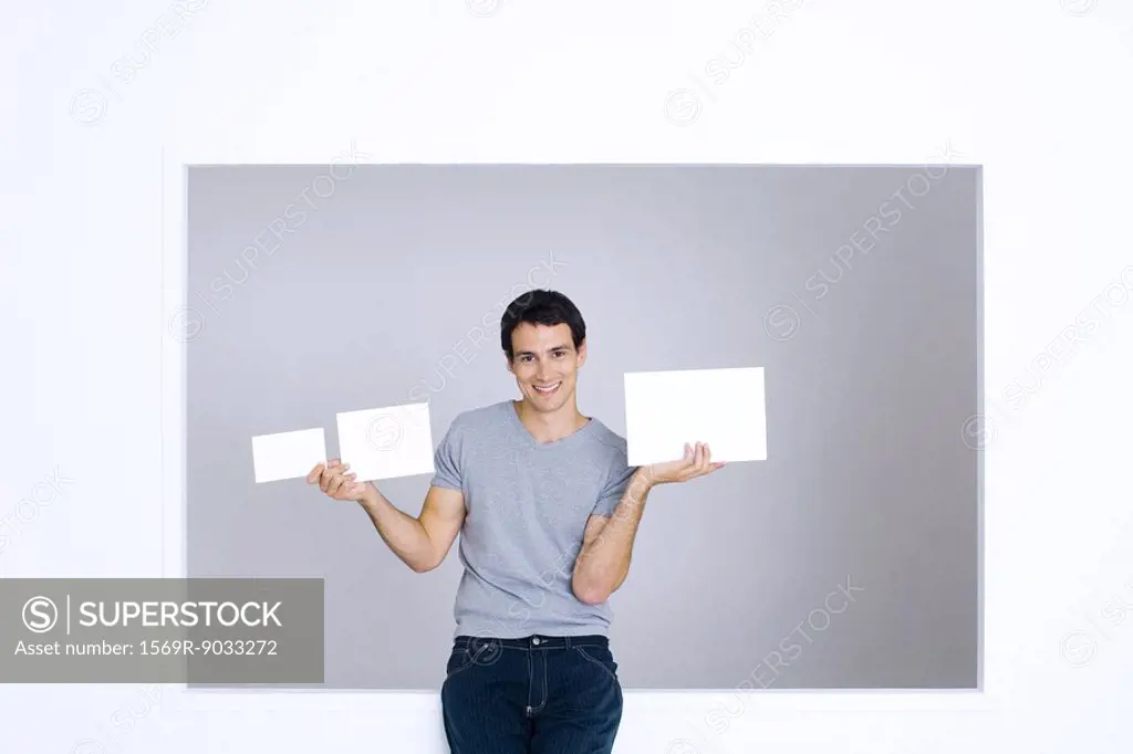 Young man holding up three blank signs of different sizes