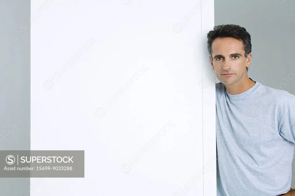 Man leaning against edge of wall, looking at camera