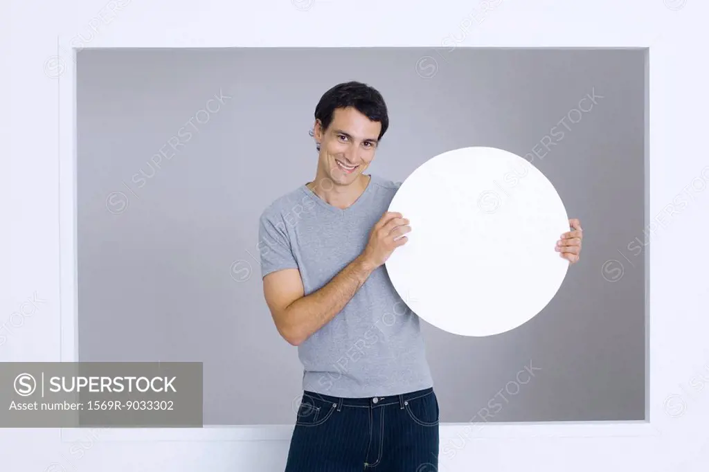 Man holding up round sign, smiling at camera