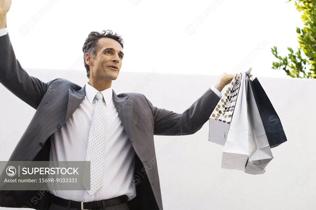 Businessman holding shopping bags, arms raised