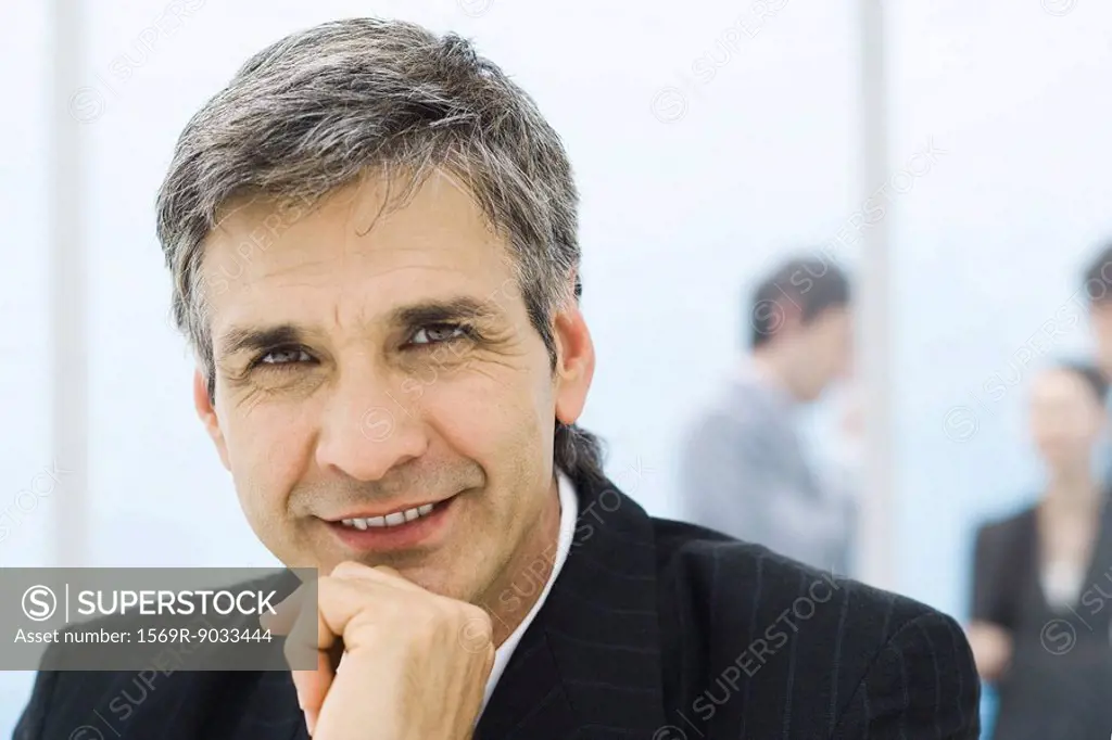 Businessman, portrait, colleagues standing in background