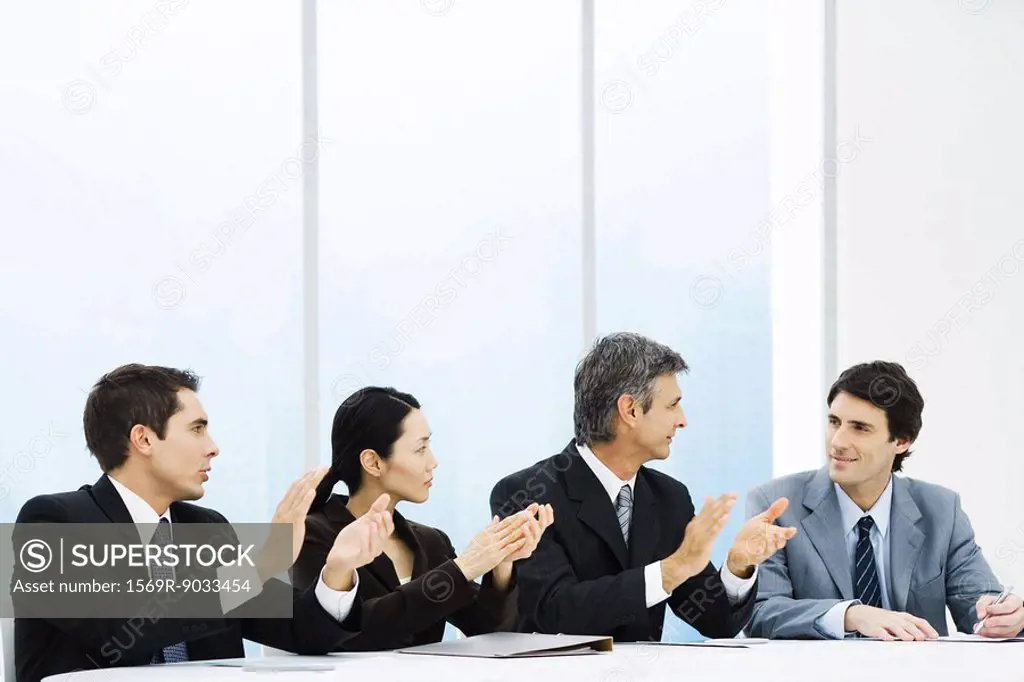 Executives applauding male colleague during meeting