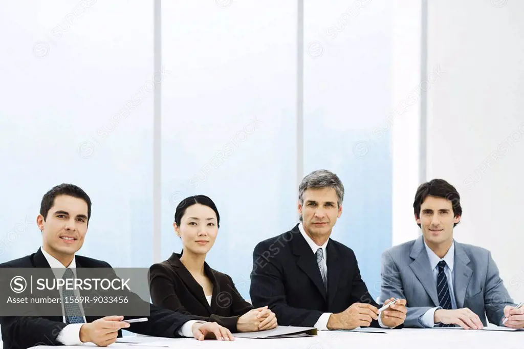 Group of business associates seated at table, looking at camera