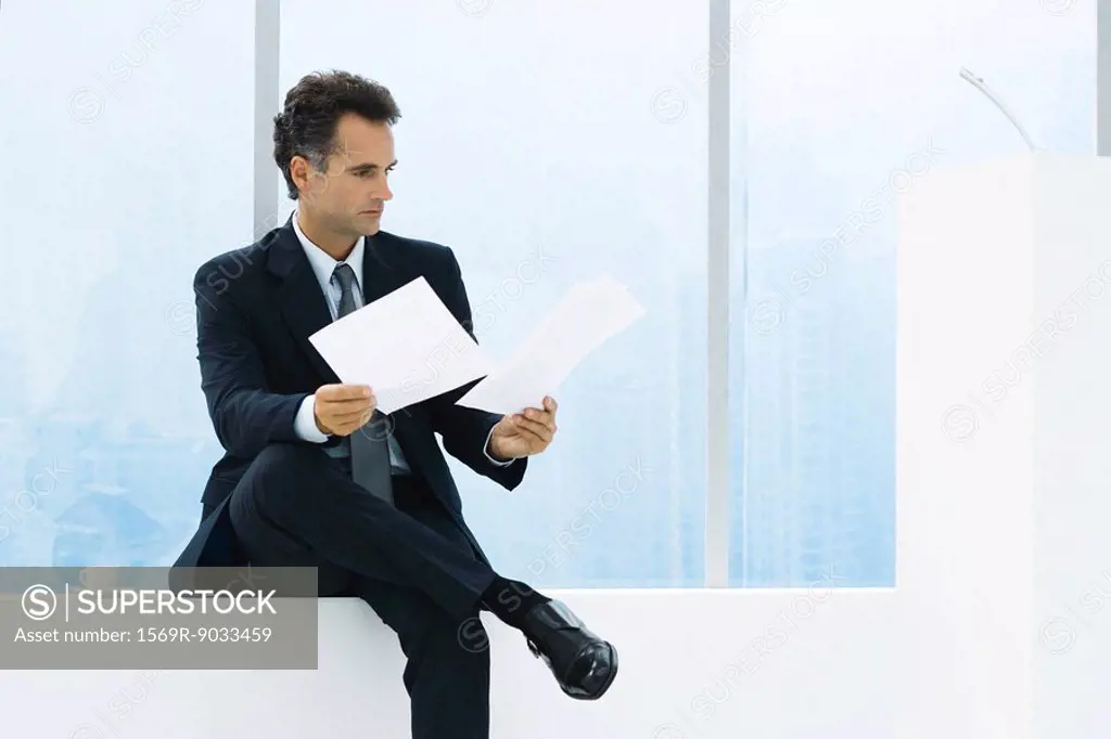 Businessman sitting by window, studying documents