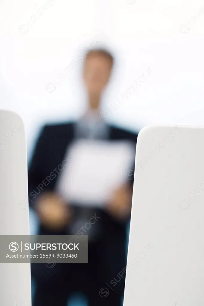 Blurred silhouette of businessman holding document, focus on foreground