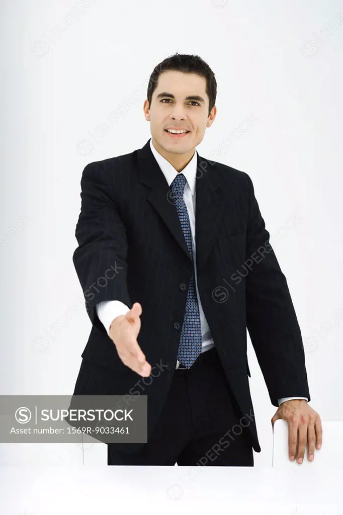 Businessman extending hand toward camera, smiling