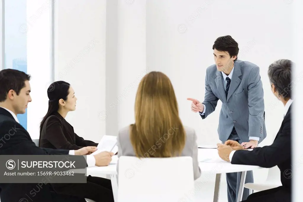 Business associates having meeting, manager leaning on table, pointing