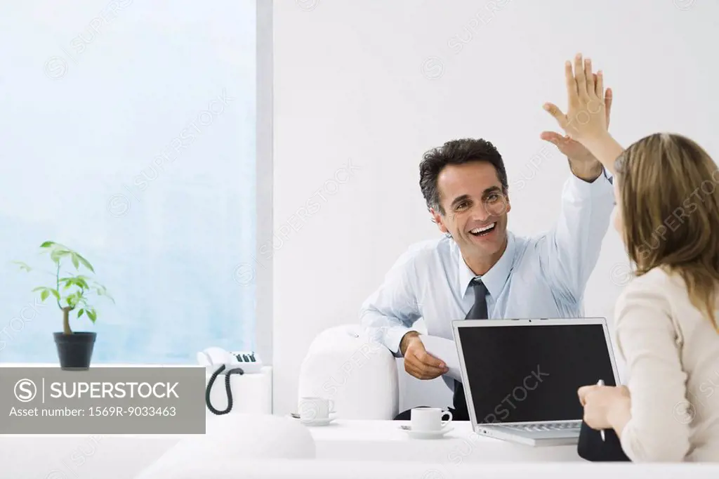 Business associates giving each other high-five in office