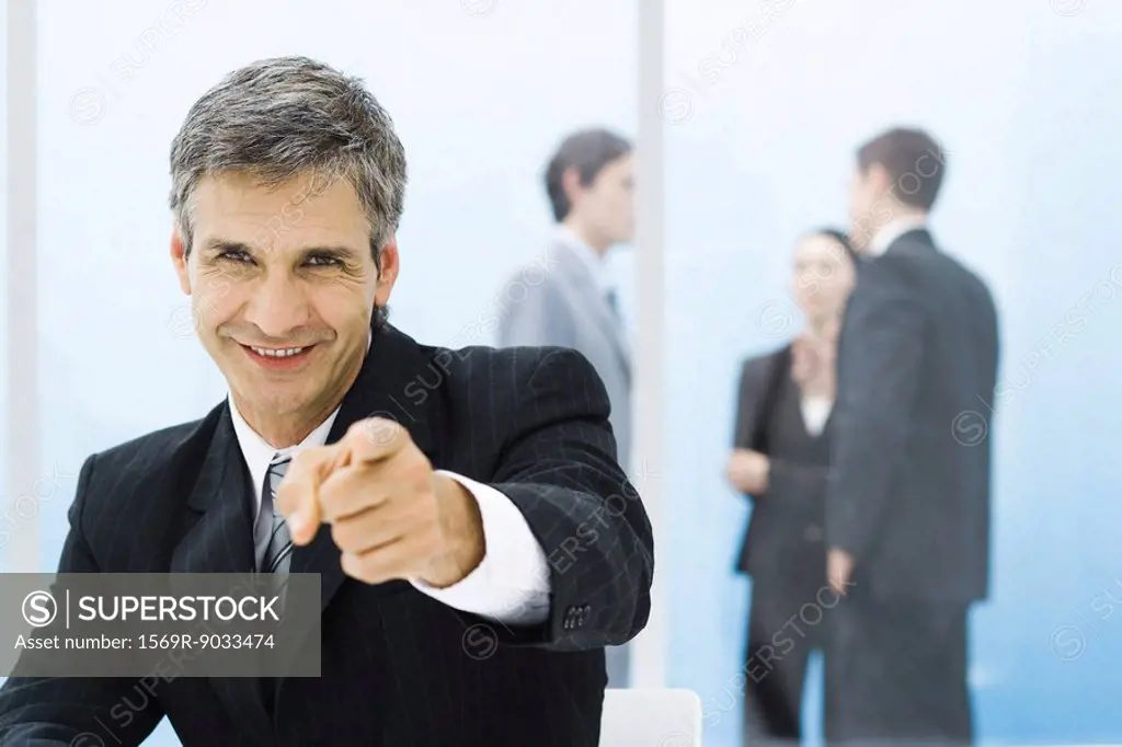 Graying businessman smiling and pointing at camera