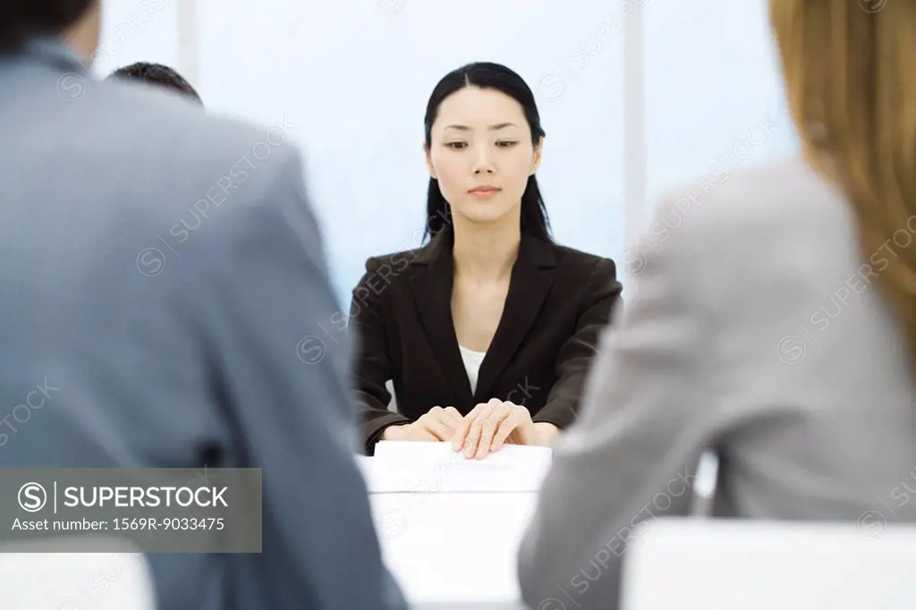 Executives in meeting, focus on businesswoman holding document in background