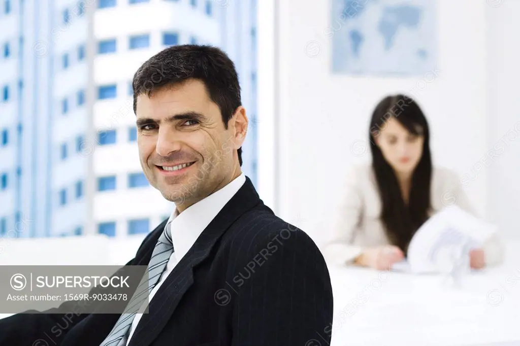Businessman in office, smiling at camera, portrait