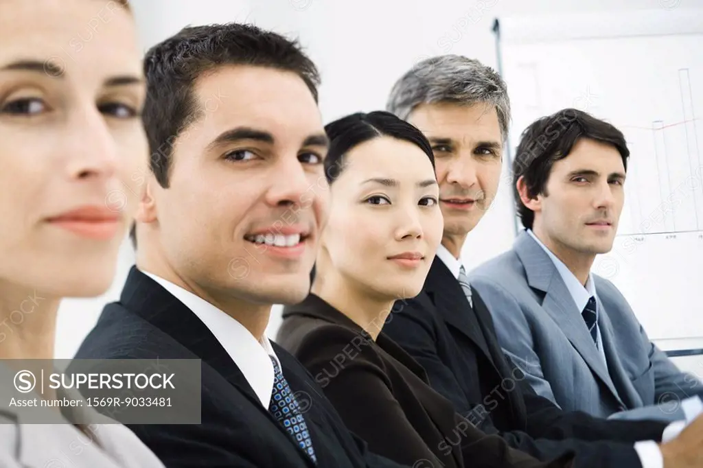 Row of business executives in conference room, smilng at camera