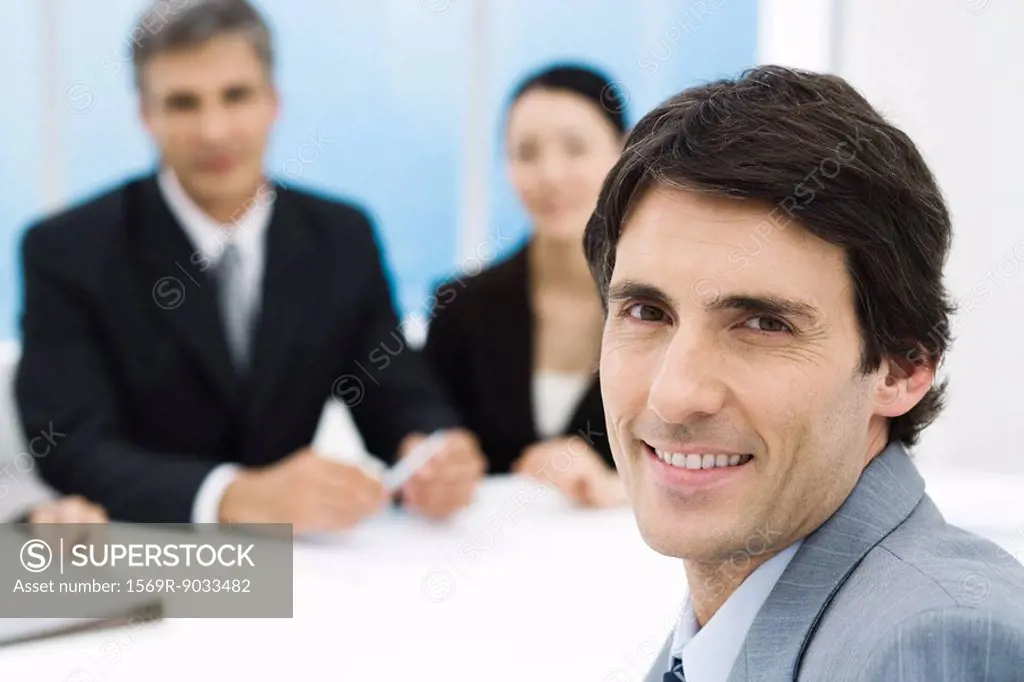 Businessman in meeting, smiling at camera