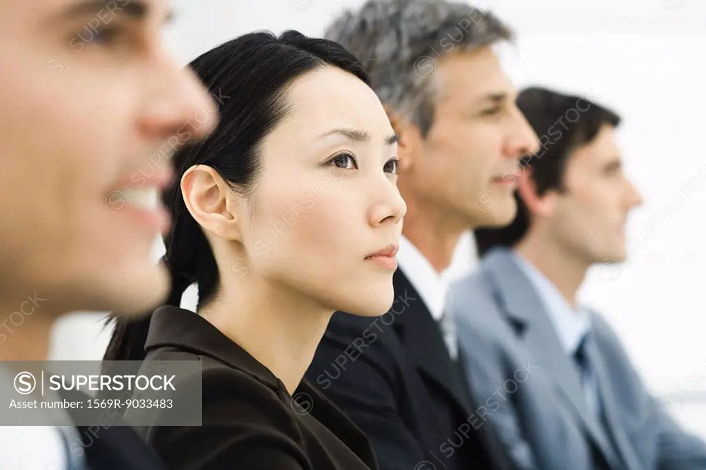 Row of business executives, focus on woman in middle ground, side view