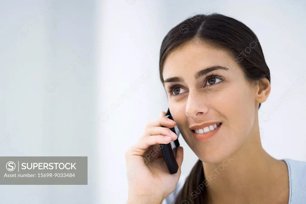 Young woman using cell phone, smiling