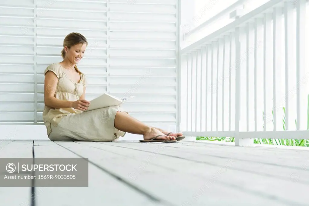 Woman sitting on porch reading book, low angle view