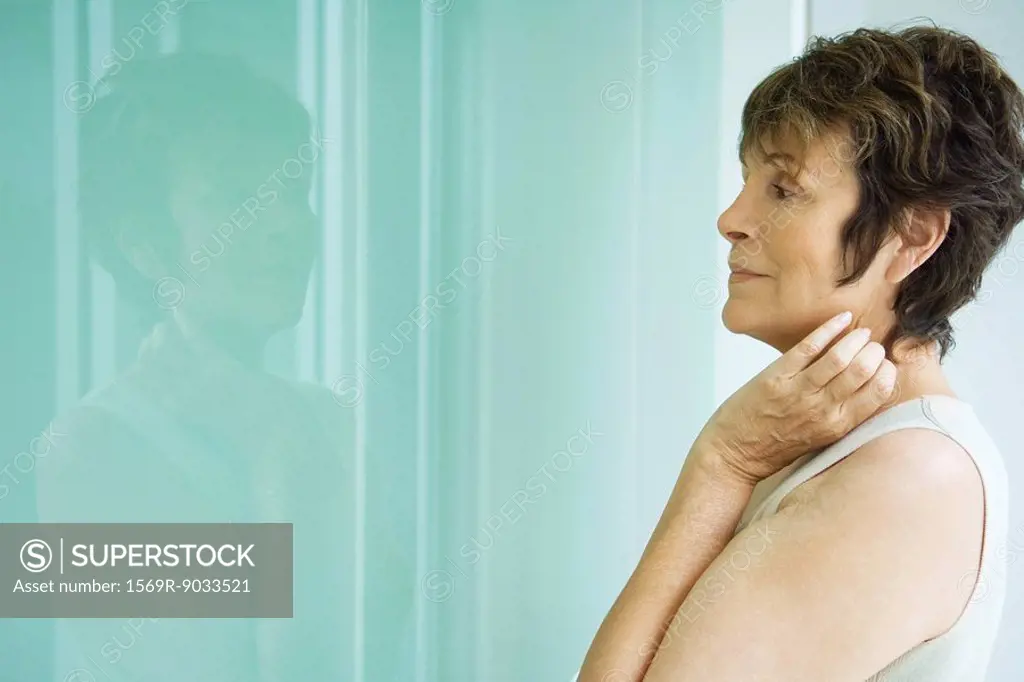 Woman looking at her reflection in window, side view