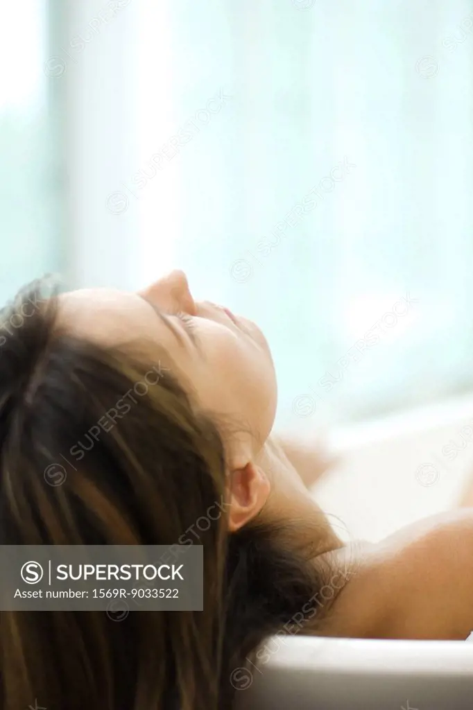 Woman in bathtub, leaning head against the side, close-up, cropped view