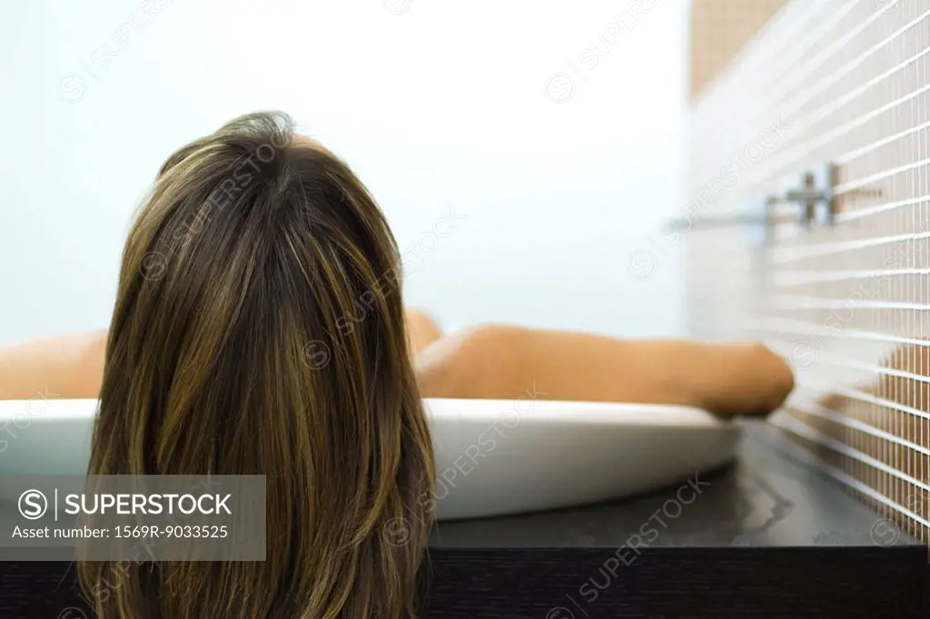 Woman in bathtub, view of back of head, close-up