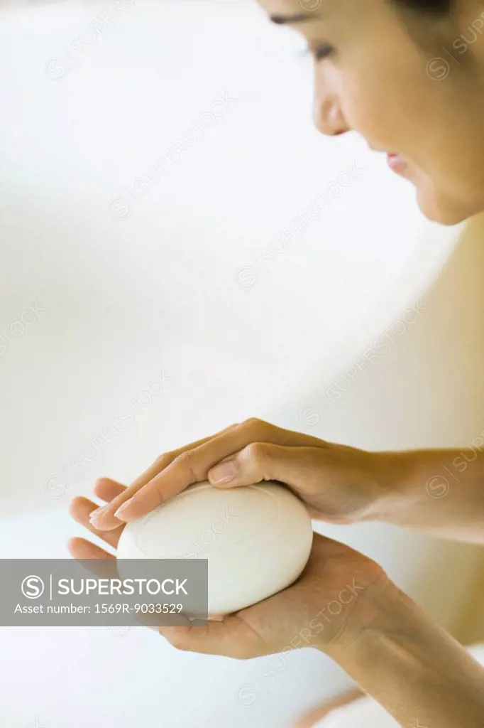 Woman holding bar of soap in hands, looking down, cropped view