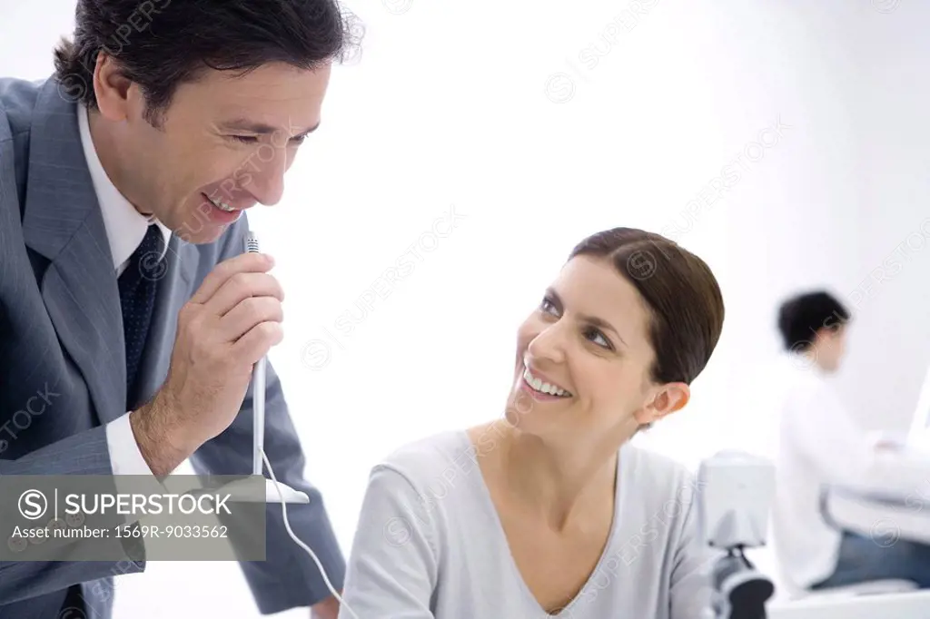 Businessman holding microphone while female colleague watches