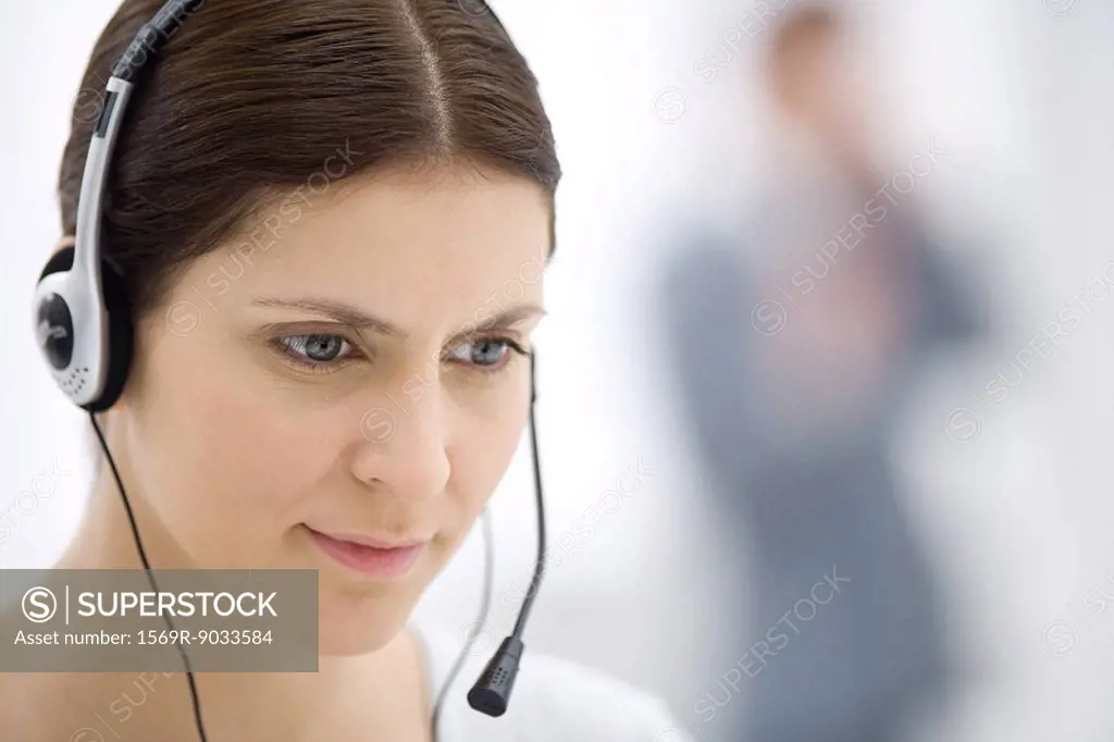 Customer service representative wearing headset, listening and looking down, close-up