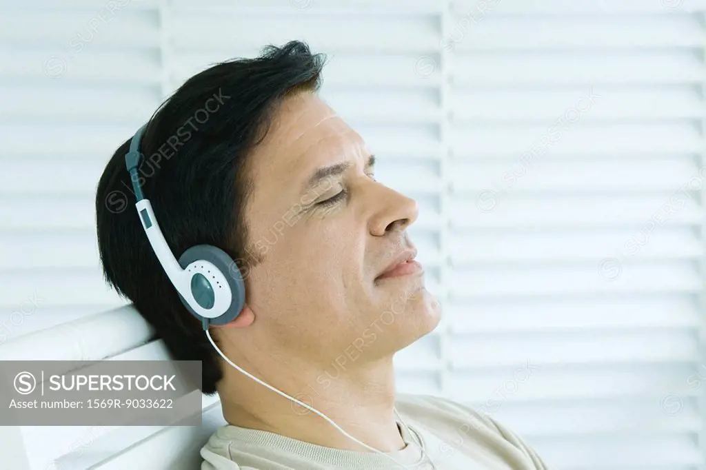 Man listening to headphones, eyes closed, profile