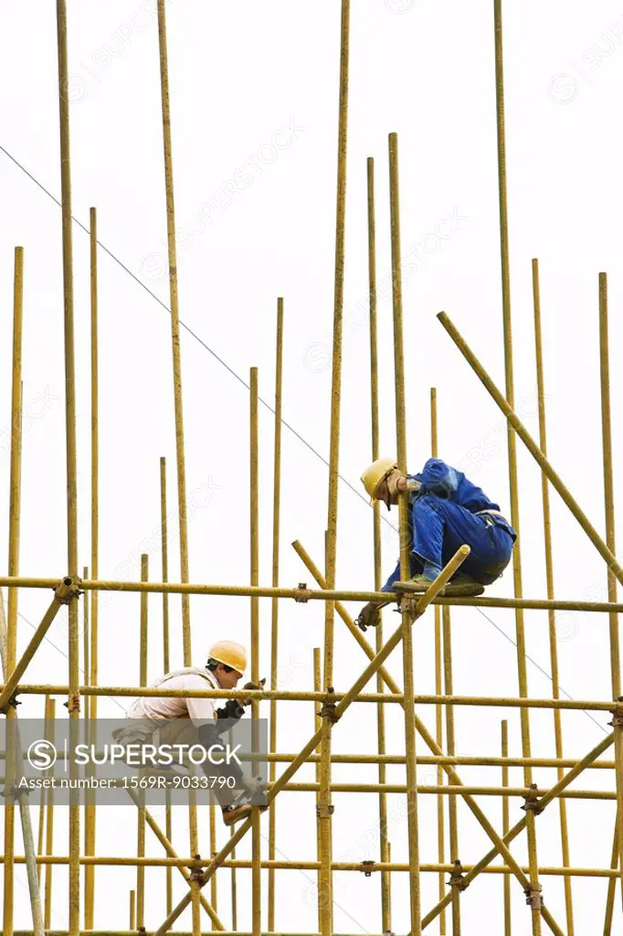 Two construction workers putting together scaffolding