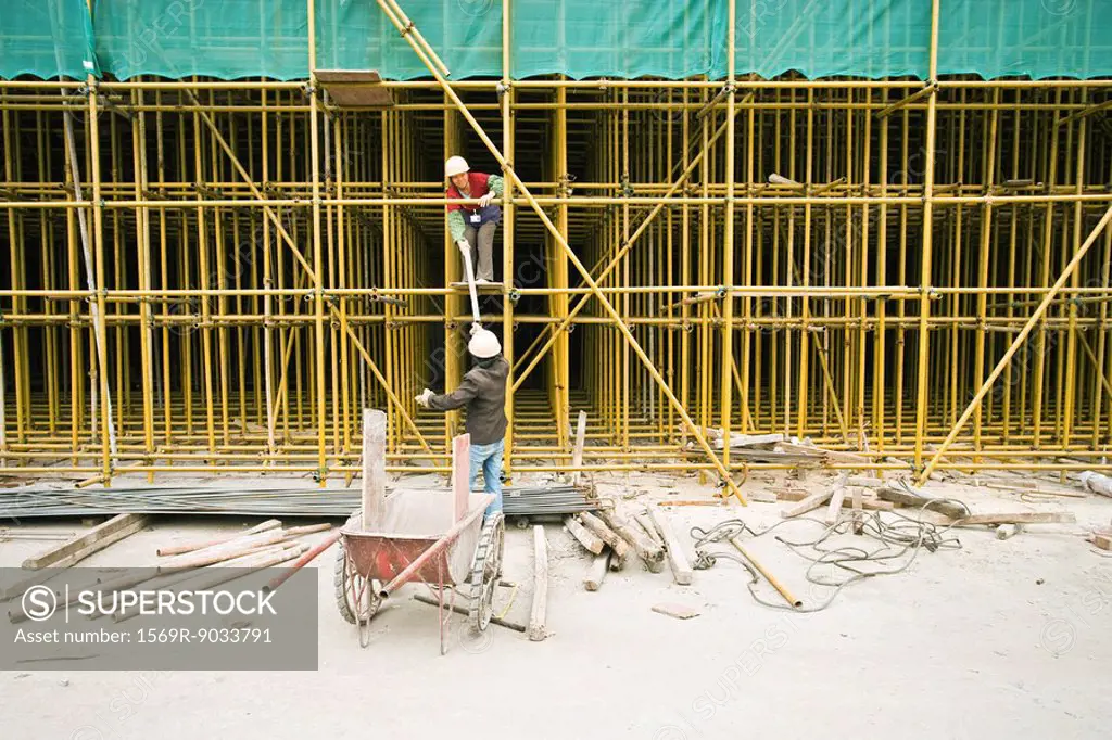 Two workers assembling scaffolding on construction site