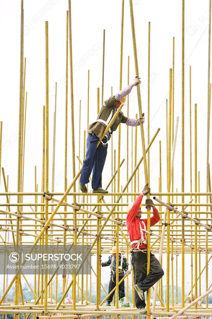Workers assembling metal scaffolding at construction site