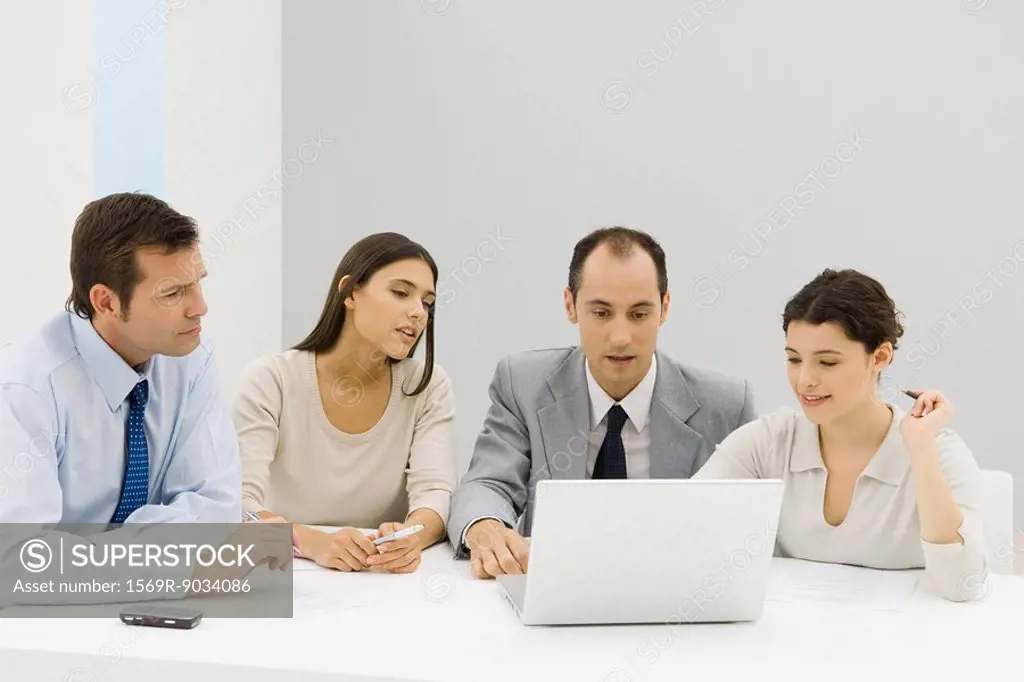 Team of business associates looking at laptop computer together in office