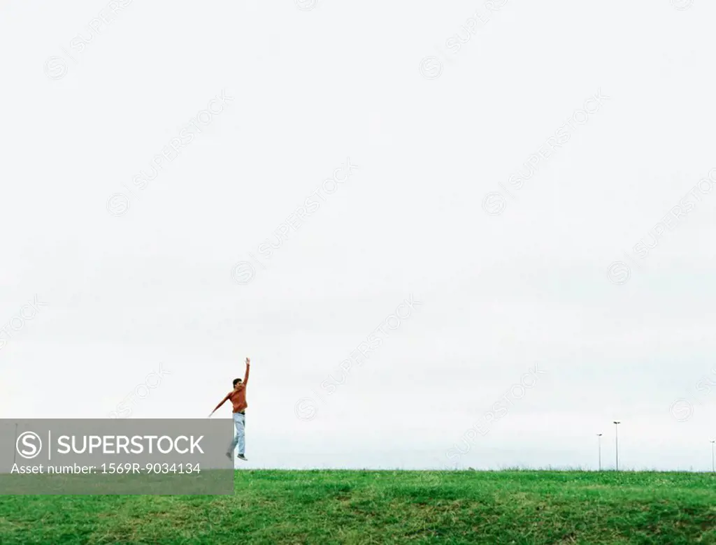 Man jumping in field, mid-distance