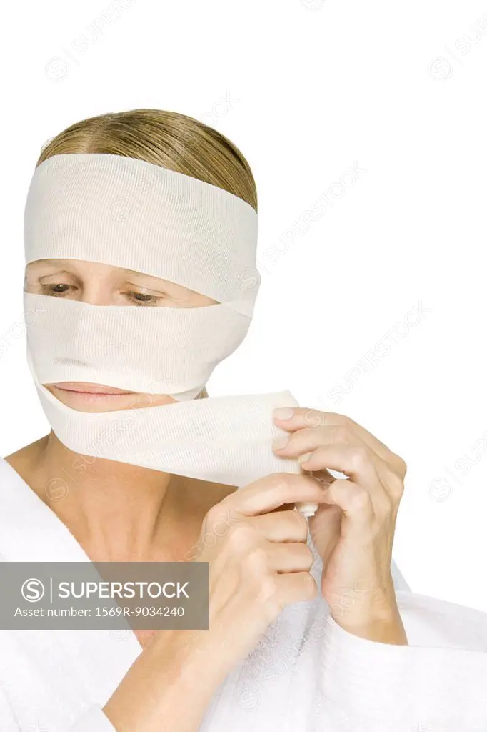 Woman removing bandages from face, looking away