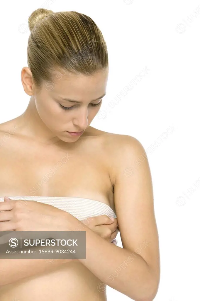 Woman covering breast with bandage, looking down