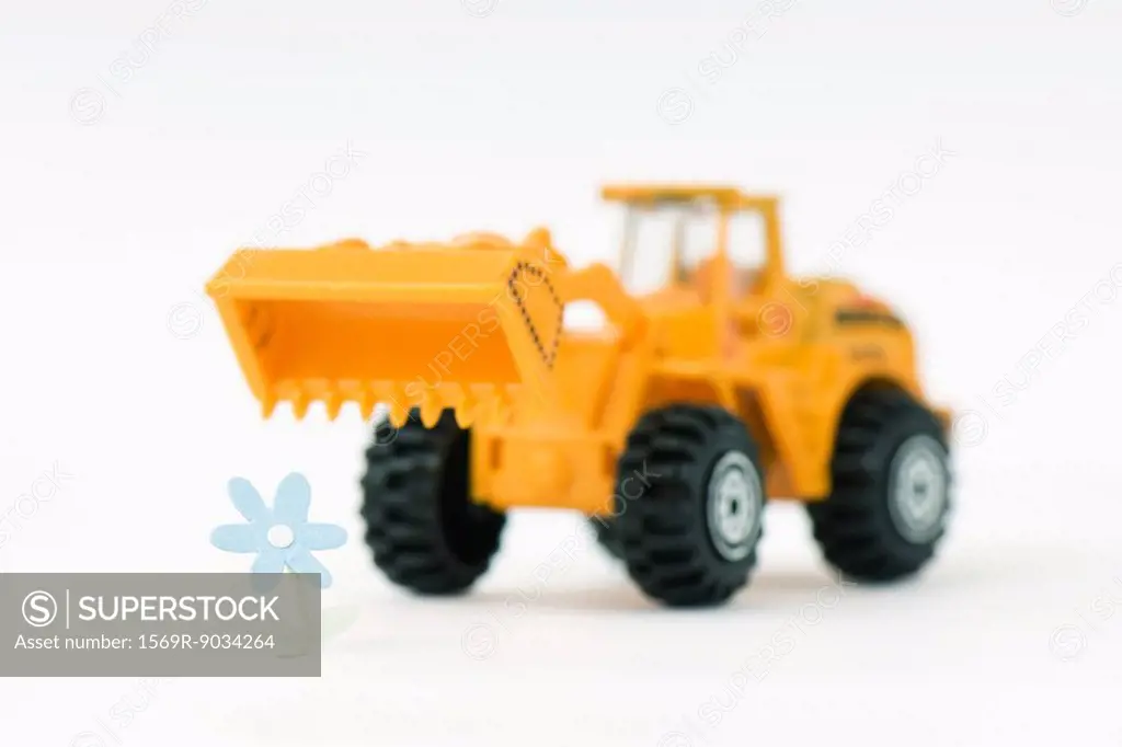 Toy bulldozer approaching flower