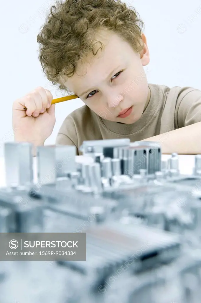 Little boy with circuit board, holding pencil, looking at camera